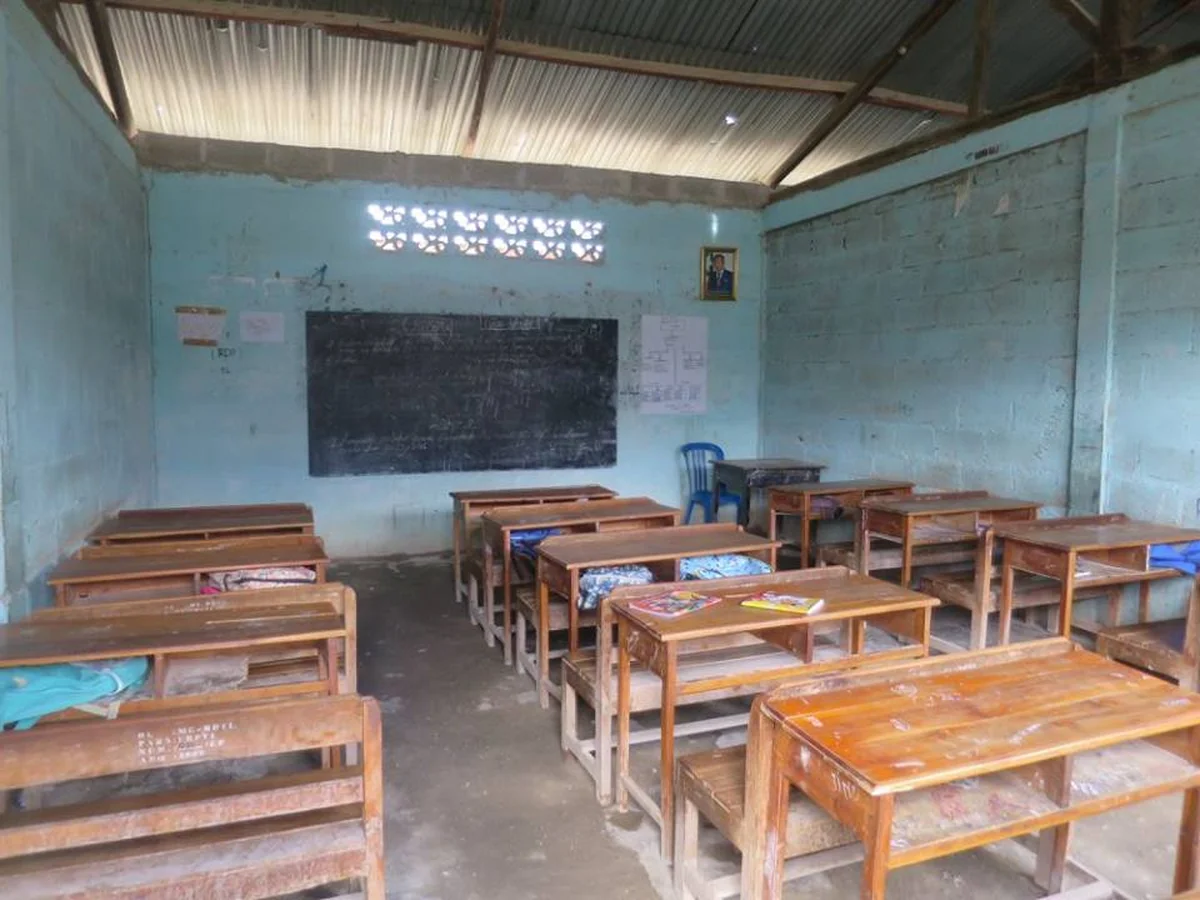 Child reading a Tetum-language primer in a classroom